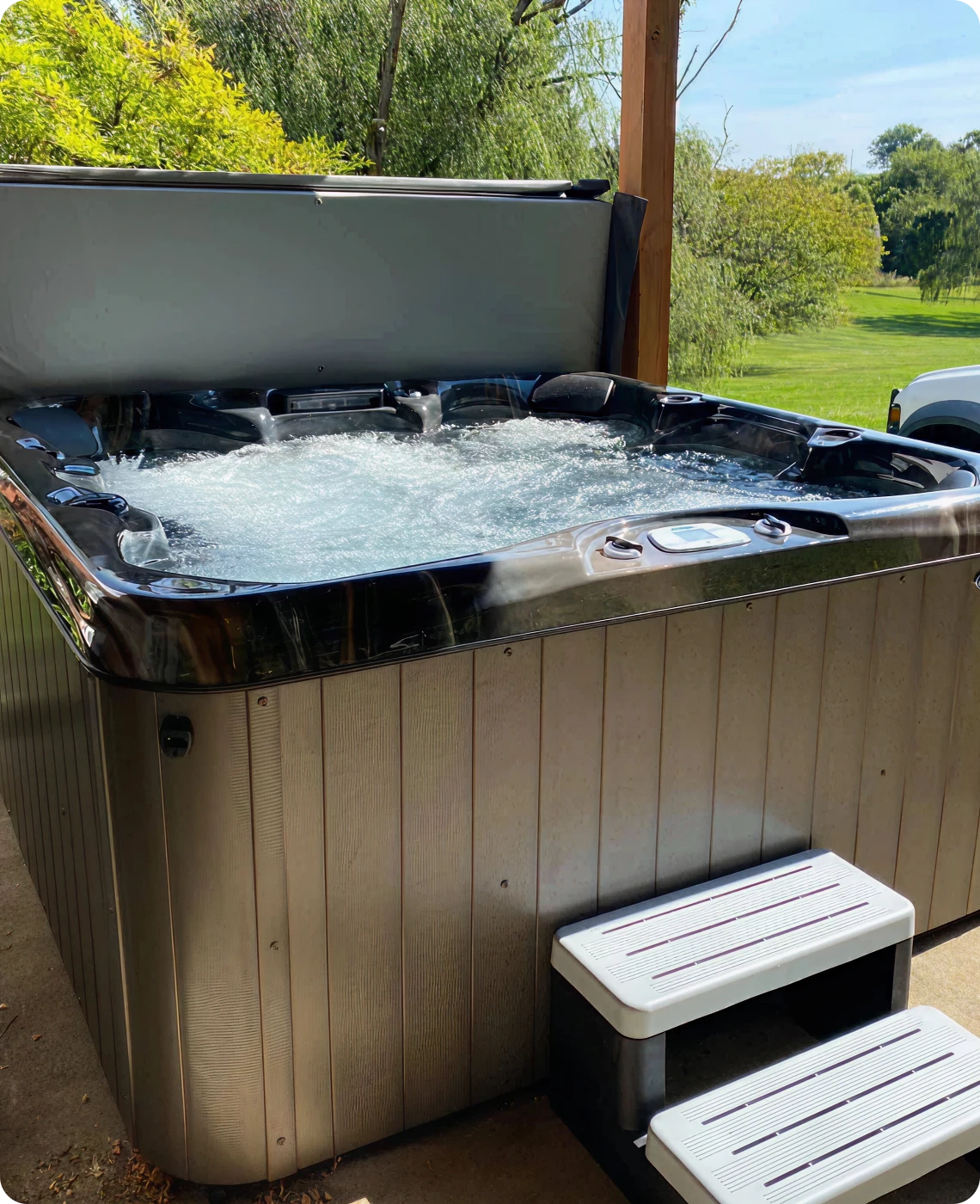 Outdoor hot tub with bubbling water and a small step stool.
