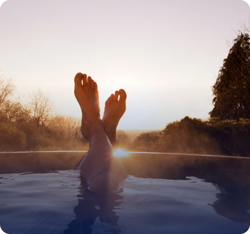 Feet relaxing above water during a serene sunset.